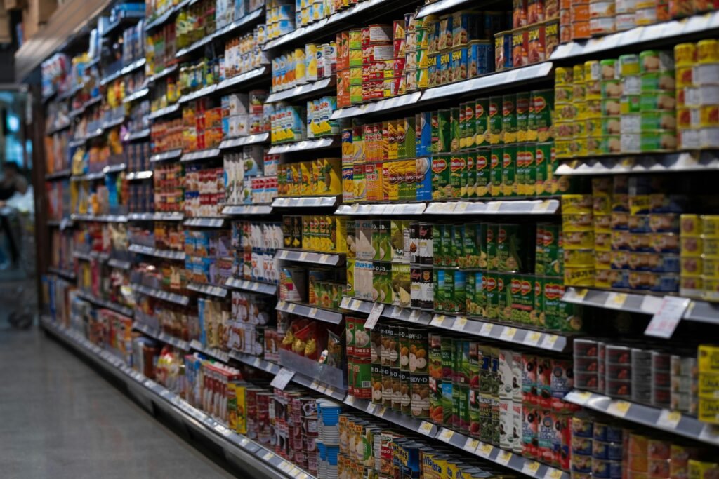 A supermarket aisle filled with various canned goods on shelves, showcasing retail diversity.